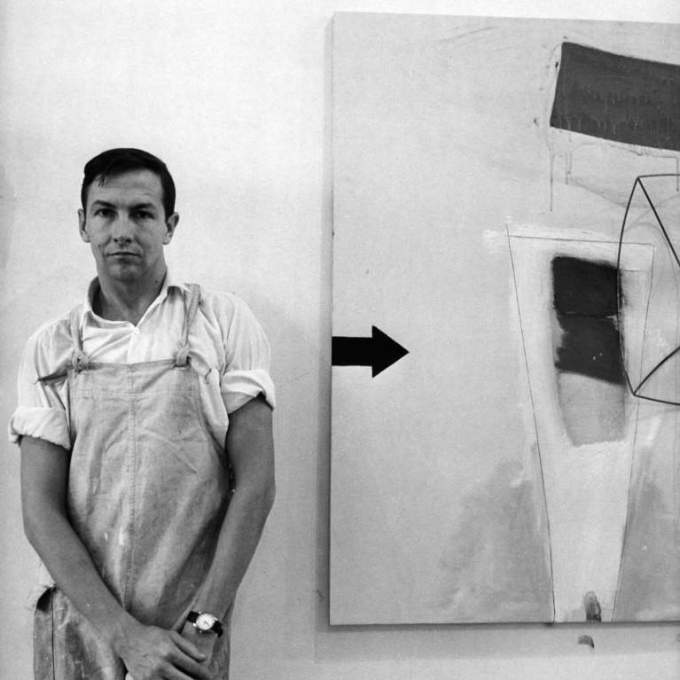 Artist Robert Rauschenberg standing next to his painting